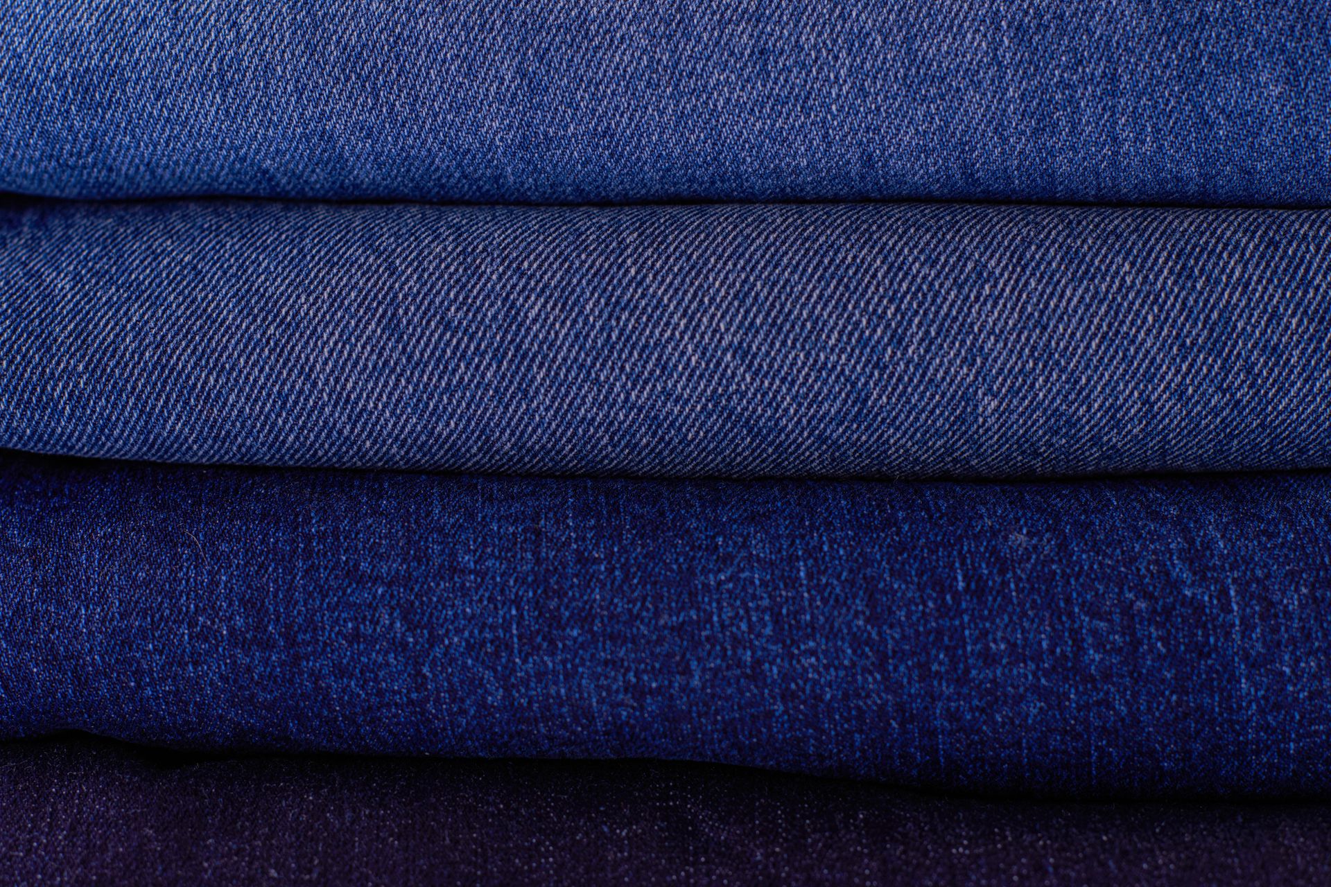 Üst üste yerleştirilmiş farklı indigo tonlarında denim kumaşlar